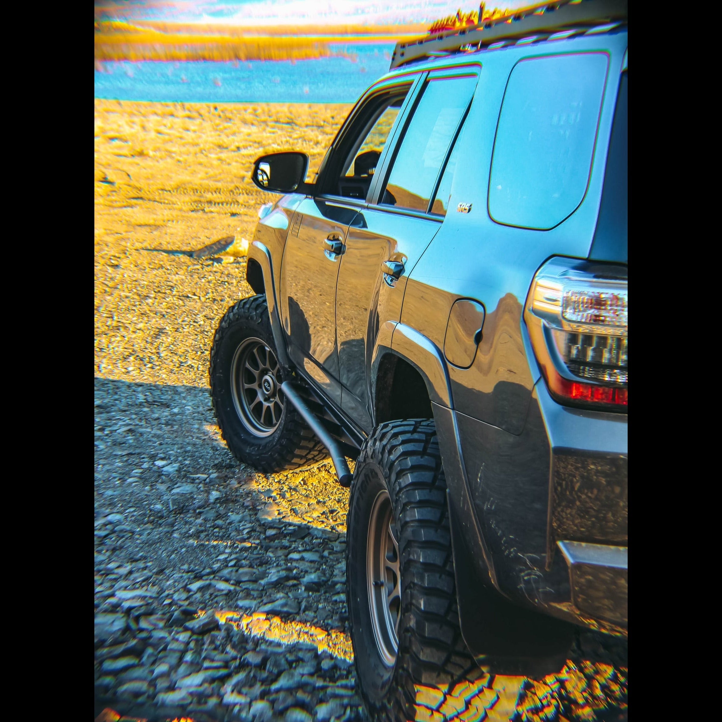 View looking down the side of a grey Toyota 4Runner overlooking a lake and equipped with C4 Rock Sliders without side steps.