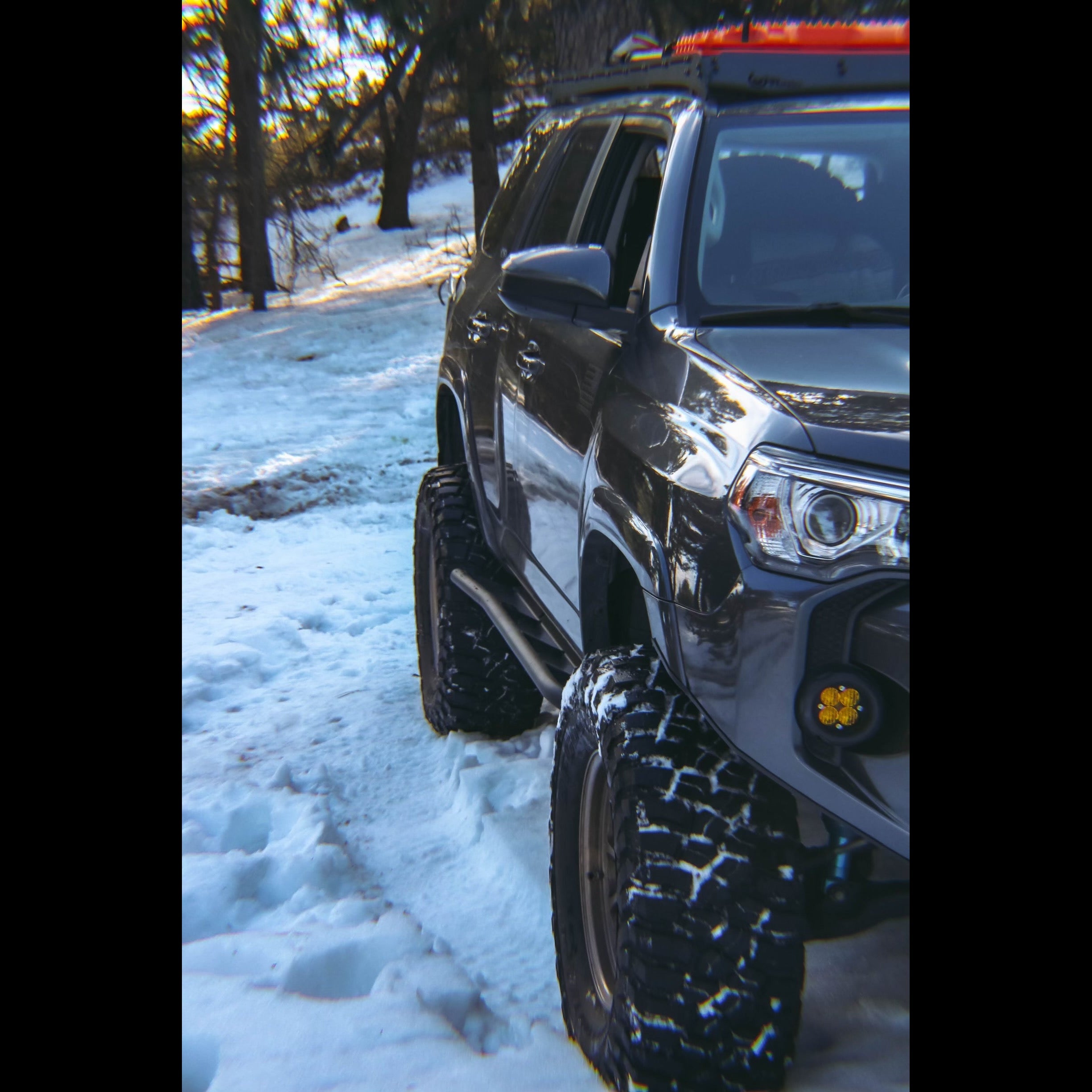 Front quartering view of a modified grey 4Runner in the snow equipped with C4 Fabrications rock sliders.