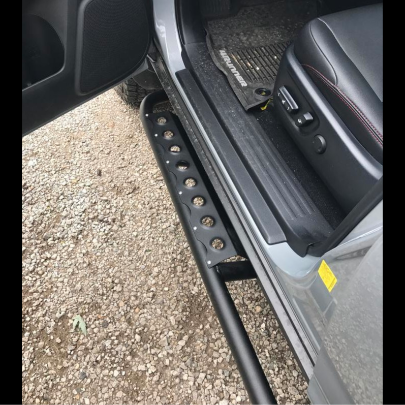 View from above of the open driver's door of a 4Runner showing the optional side step installed on C4 Fabrication's rock sliders.