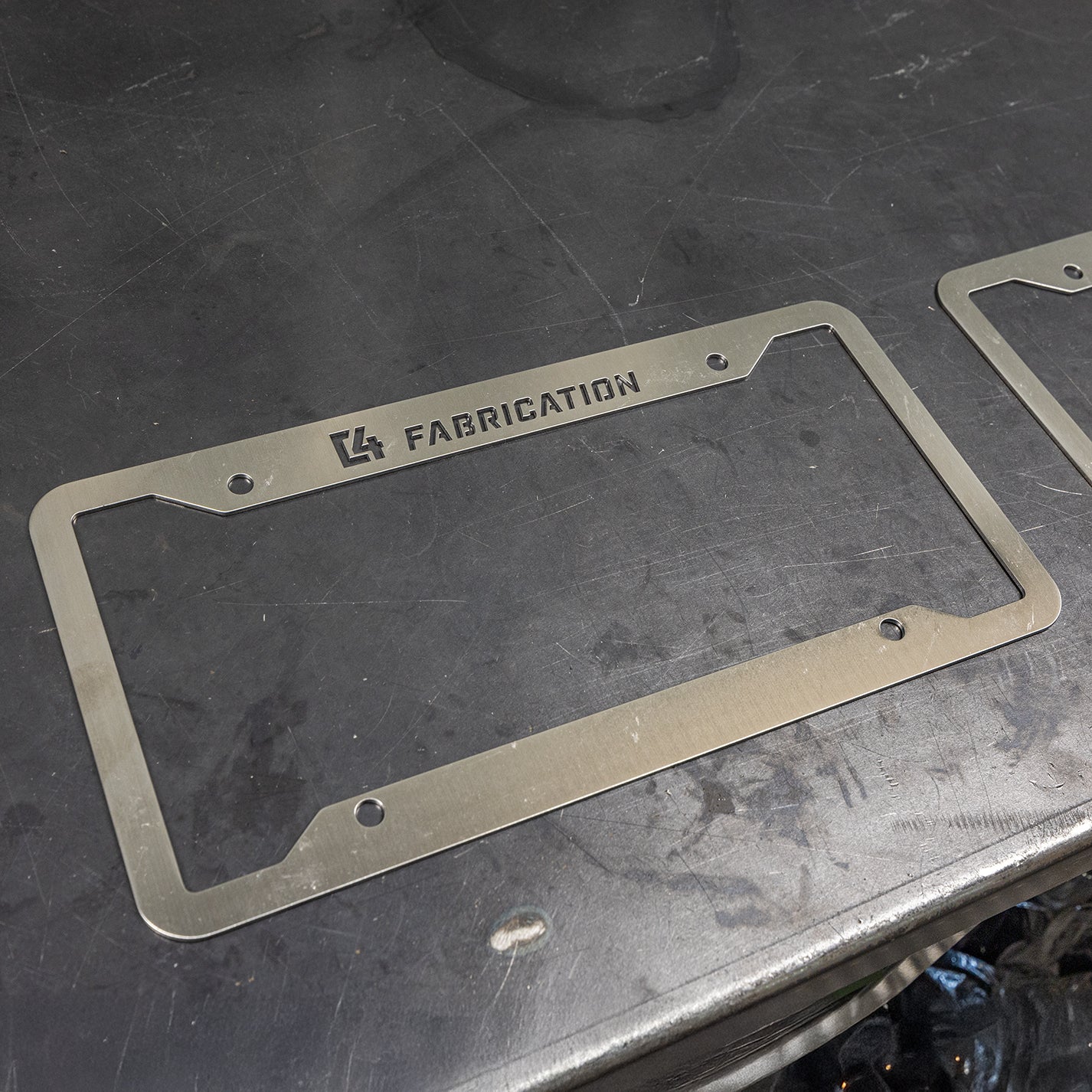 C4 License Plate Frame at an angle layed flat on a steel table.