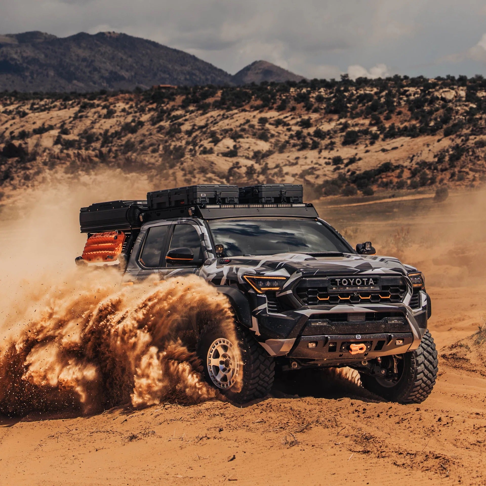 Toyota truck driving on a dirt road with mountains in the background